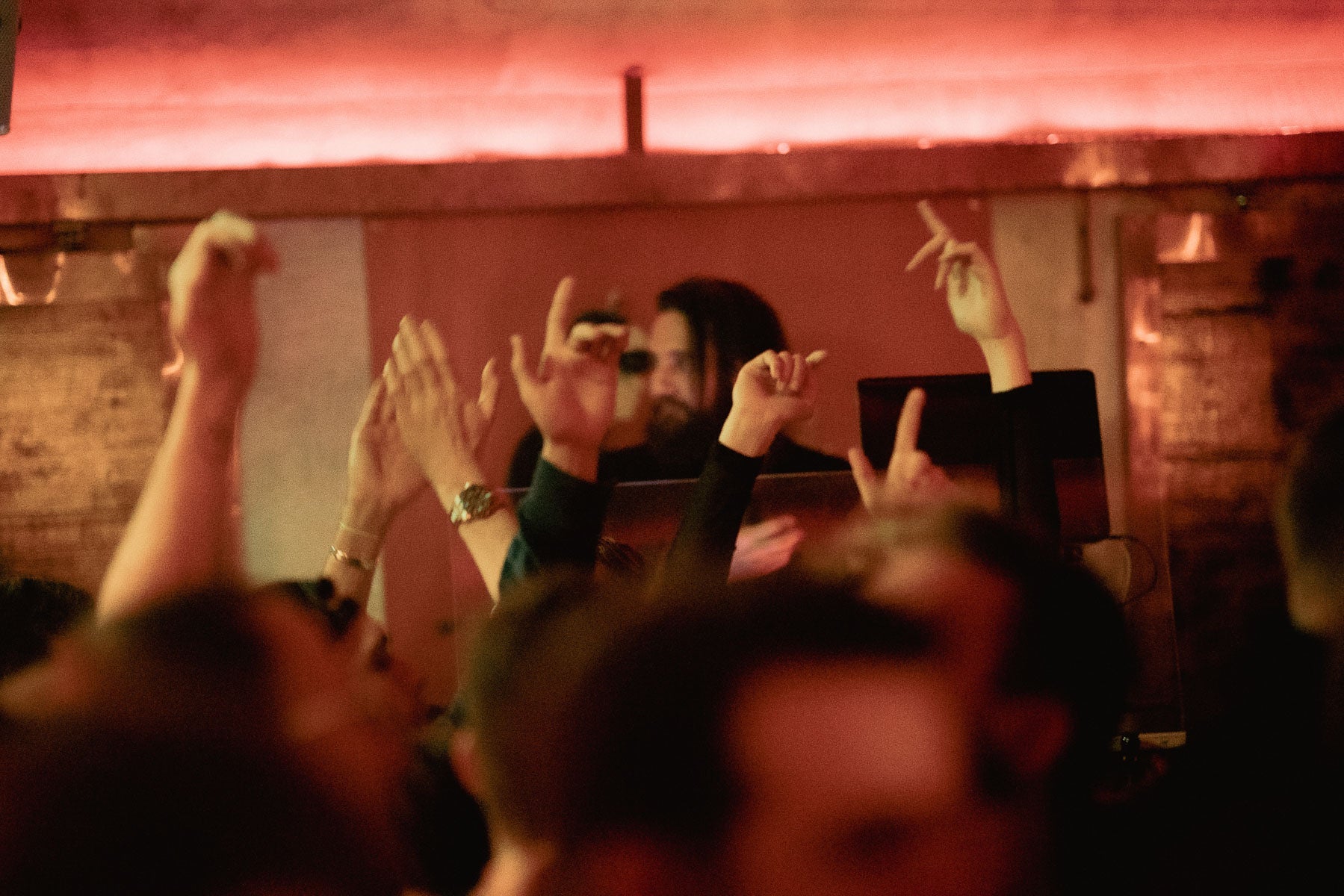 Tanzende Gäste mit erhobenen Armen vor dem DJ-Pult in der Boazn – Tanzbar an der Isar in München