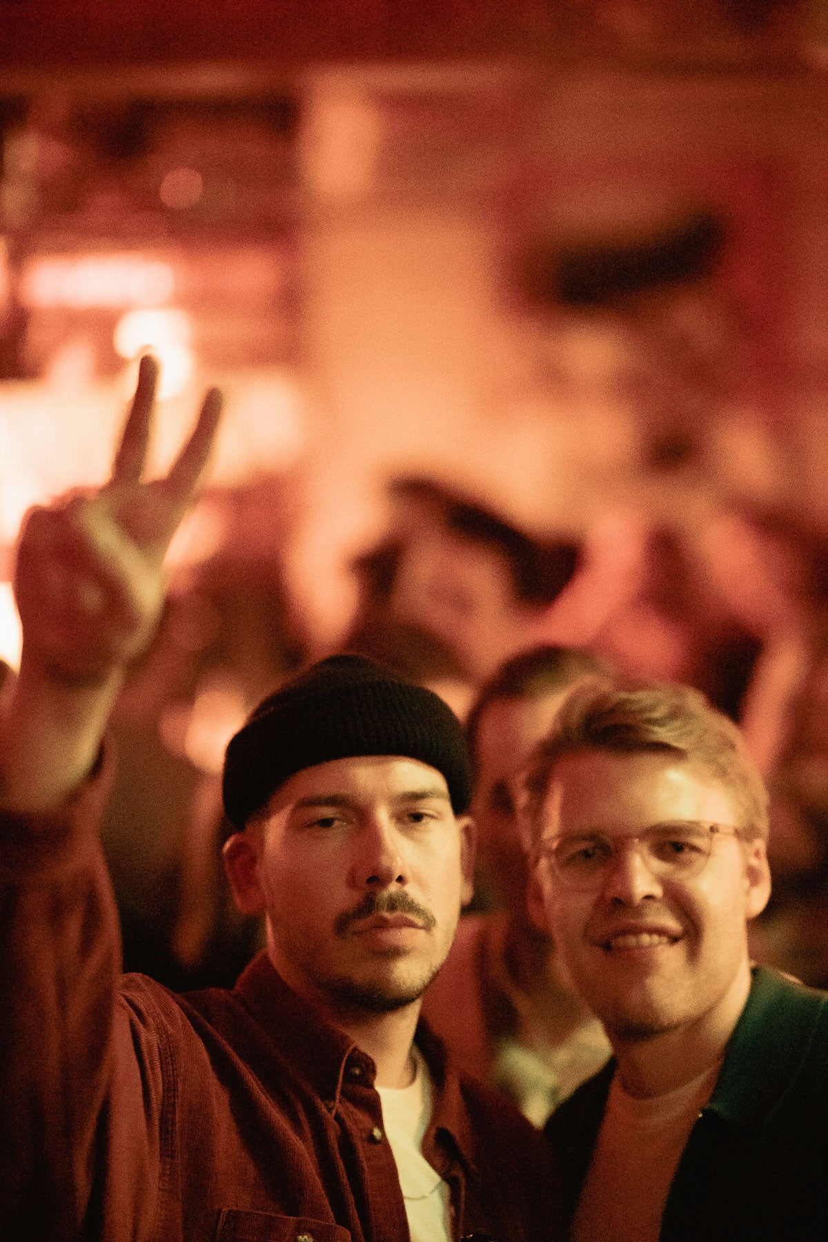 Zwei Freunde lachen in die Kamera, Peace-Zeichen unter warmem Licht – Boazn München, Dezember 2025