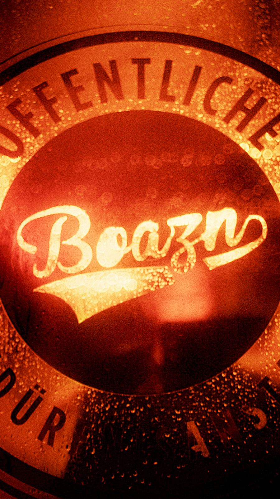 Boazn-Logo „Öffentliche Bedürfnisanstalt“ glüht orange auf einer Bierflasche – Bar in München, Februar 2026