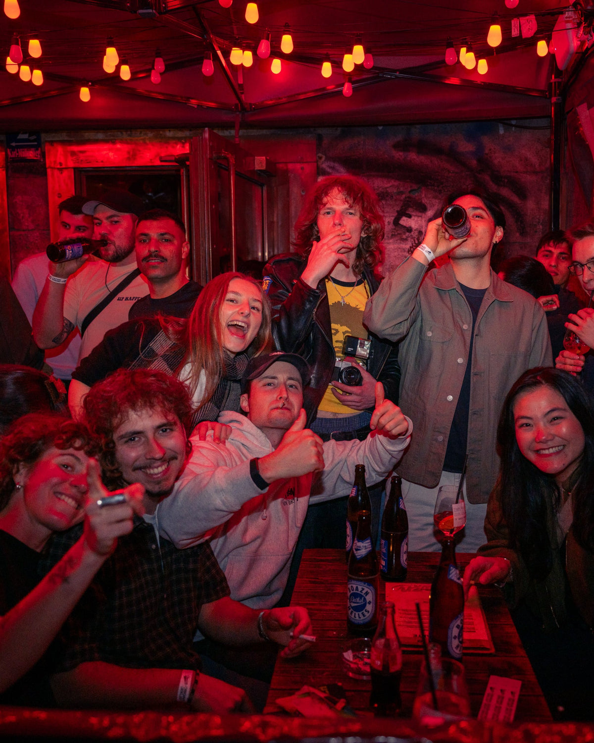 Große Gruppe in der Boazn München mit Boazn-Helles am Tisch unter Lichterkette — Munich Boazns Cult and culture