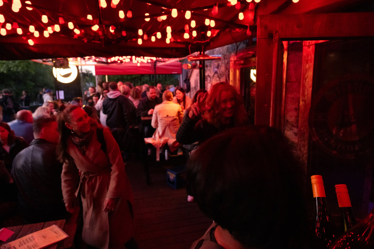 Volle Boazn-Terrasse am Abend unter roter Lichterkette — Bar in Au-Haidhausen München an der Isar