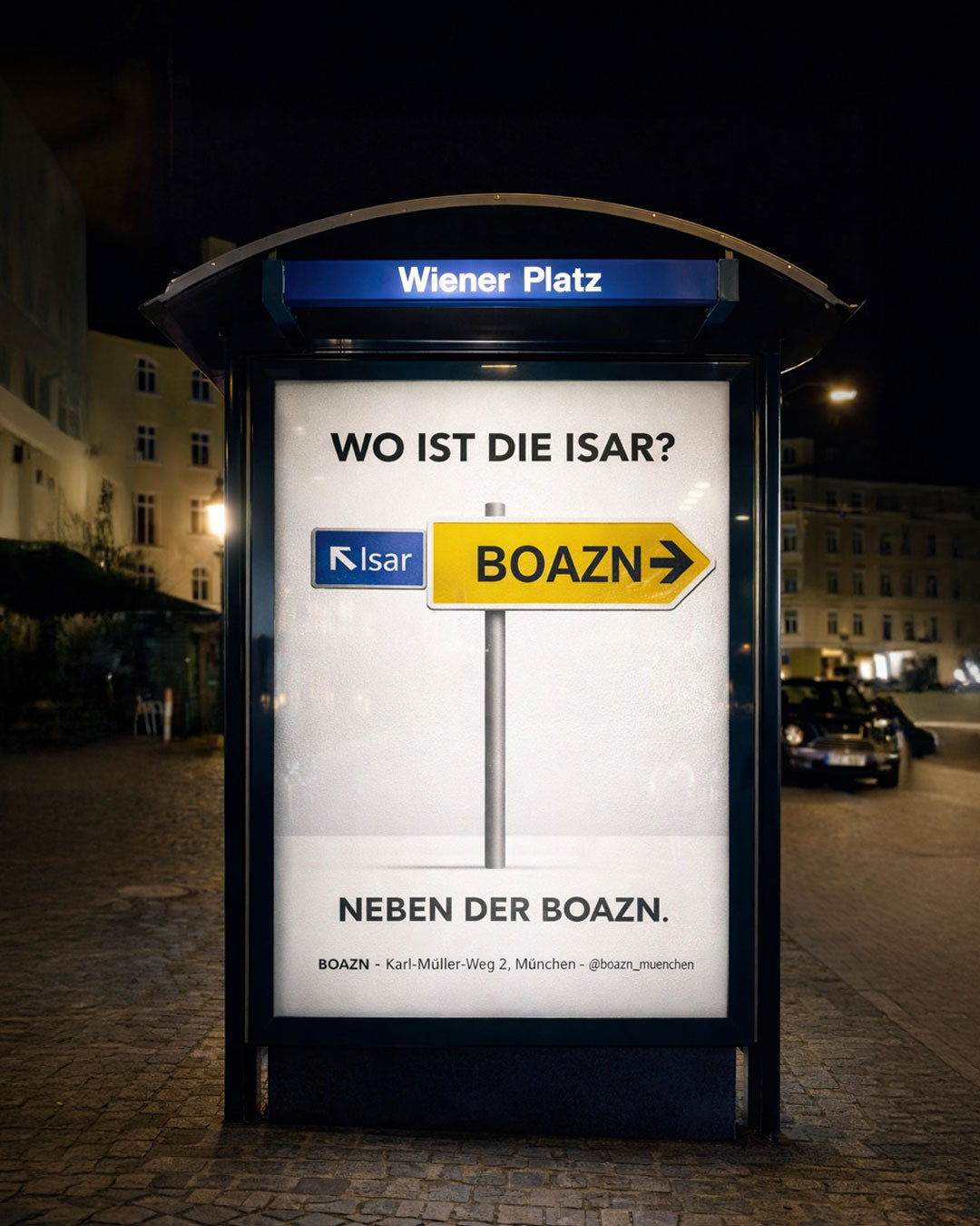 Boazn-Plakatwerbung am Wiener Platz in München mit Wegweiser 'Wo ist die Isar? Neben der Boazn'