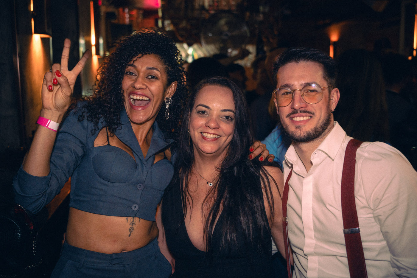 Drei Gäste lachen ausgelassen, Frau links zeigt Peace-Zeichen, vor der Boazn-Bar – Nightlife München, Februar 2026 24