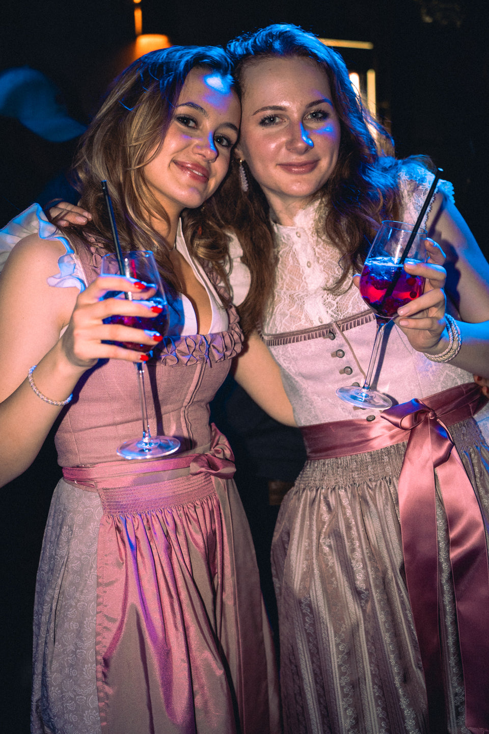 Zwei junge Frauen in rosa Dirndln prosten mit Cocktails in die Kamera – Boazn München, Februar 2026