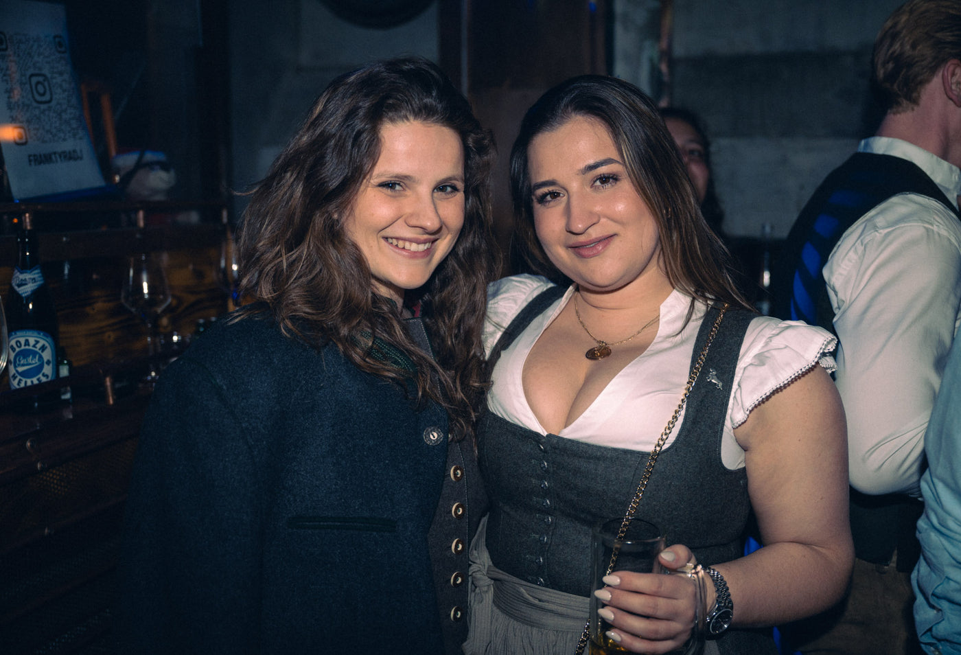 Zwei Freundinnen, eine im grauen Dirndl, lächeln vor der Boazn-Bar – Nightlife München, Januar 2026 16