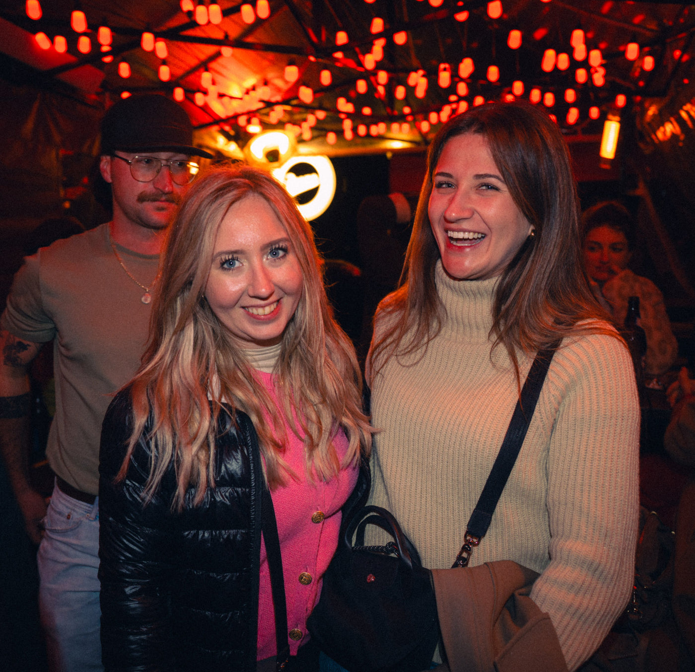 Zwei Freundinnen lachen unter Lichterketten und Boazn-Neonsign – Boazn München, Januar 2026 17