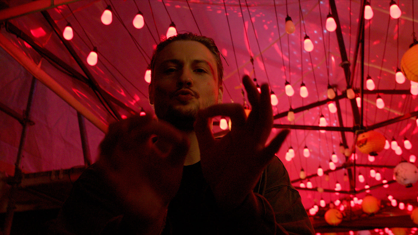 Gast formt mit den Händen ein Zeichen unter rosa Lichterketten – Halloween 2025, Boazn München 19