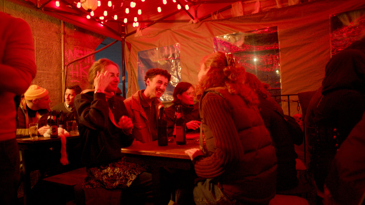 Gäste sitzen lachend am Tisch auf der Terrasse – Halloween 2025, Kneipe an der Ludwigsbrücke 27