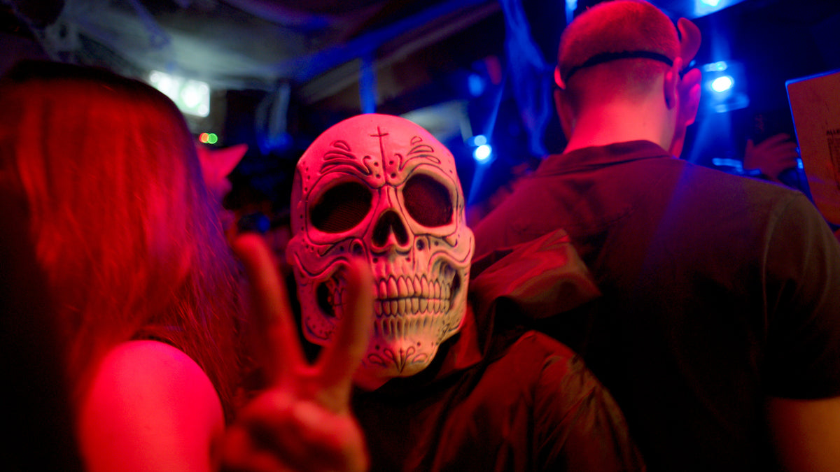Gast mit Sugar-Skull-Maske zeigt das Peace-Zeichen – Halloween 2025, Bar an der Ludwigsbrücke 44