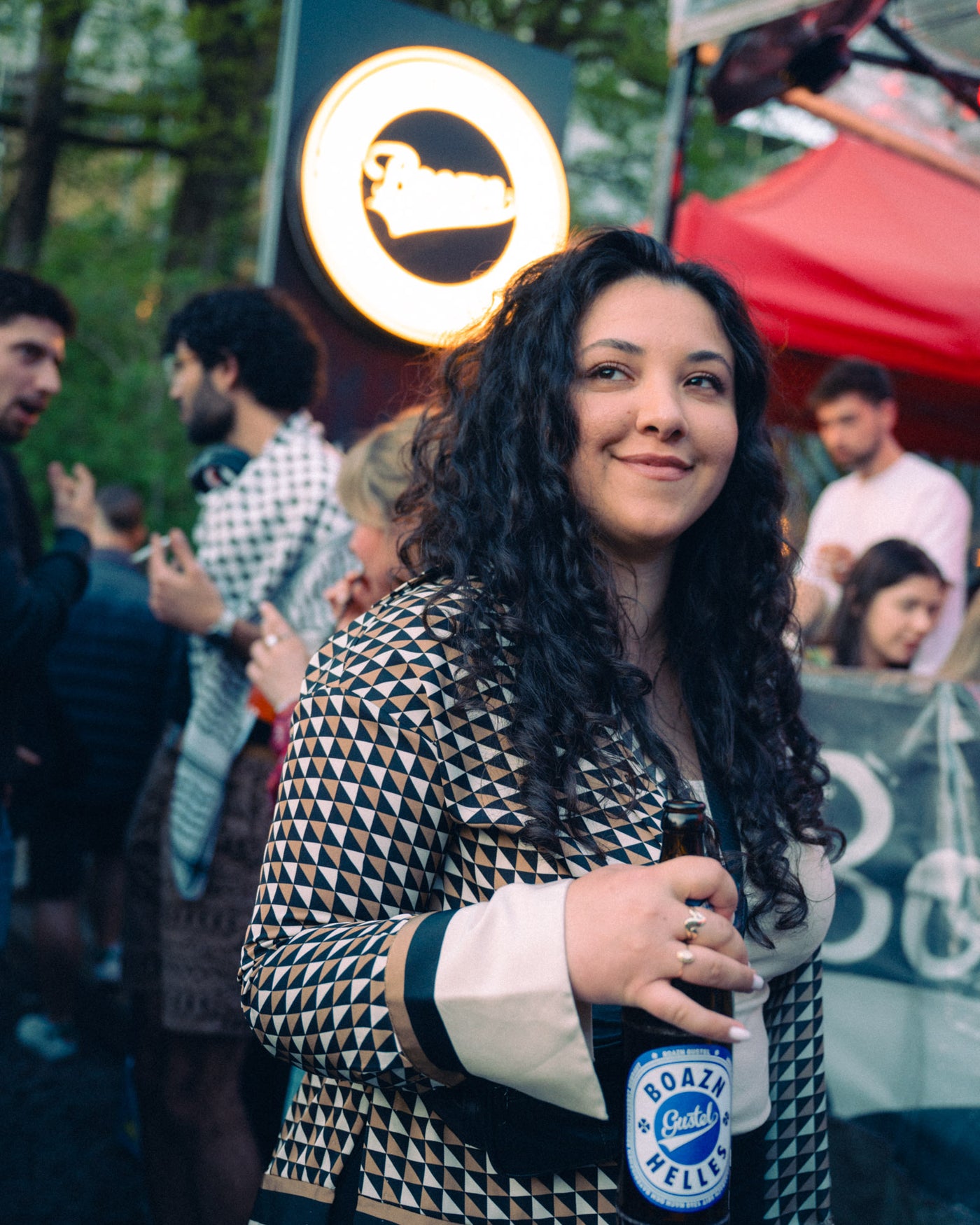 Gast mit Boazn Helles vor leuchtendem Boazn-Logo auf der Terrasse – München, April 2026 17