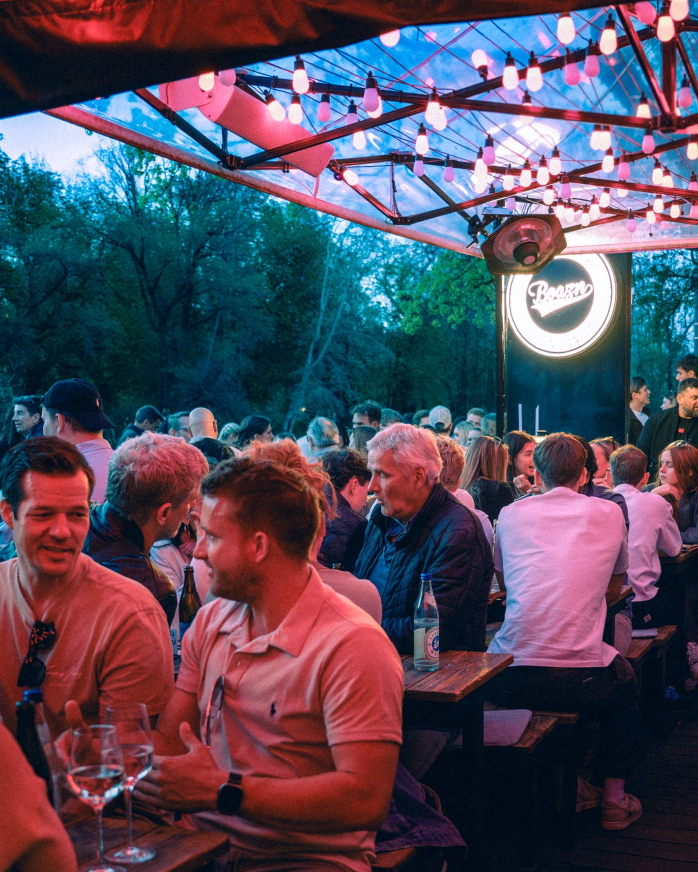Boazn-Terrasse am frühen Abend mit Lichterketten, Bierbänken und Logo – München, April 2026 18
