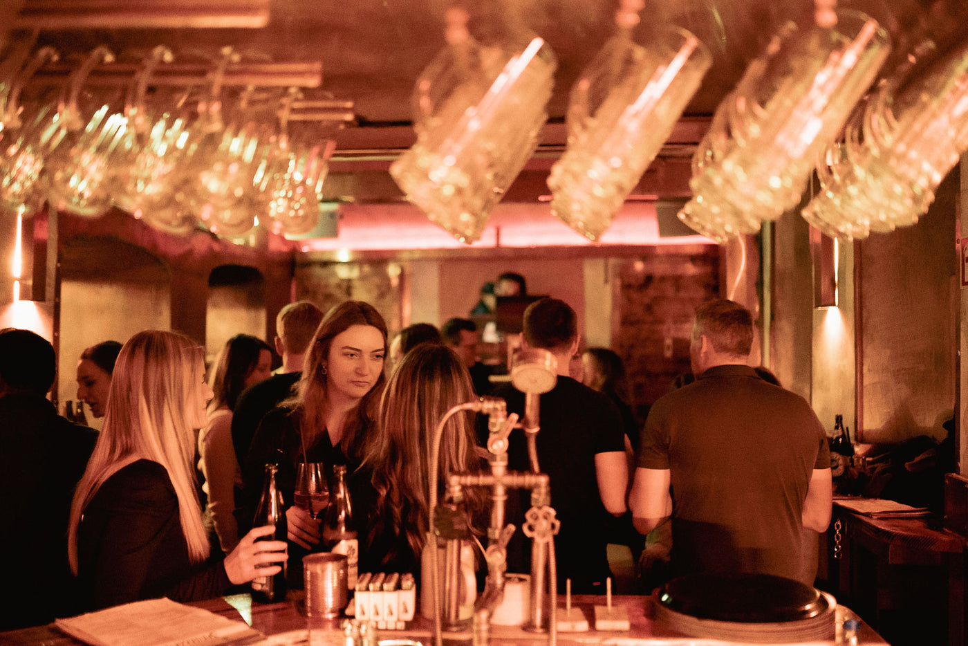 Gut gefüllte Bar mit Gästen unter dem Gläserregal – Boazn München, Winterabend Dezember 2025