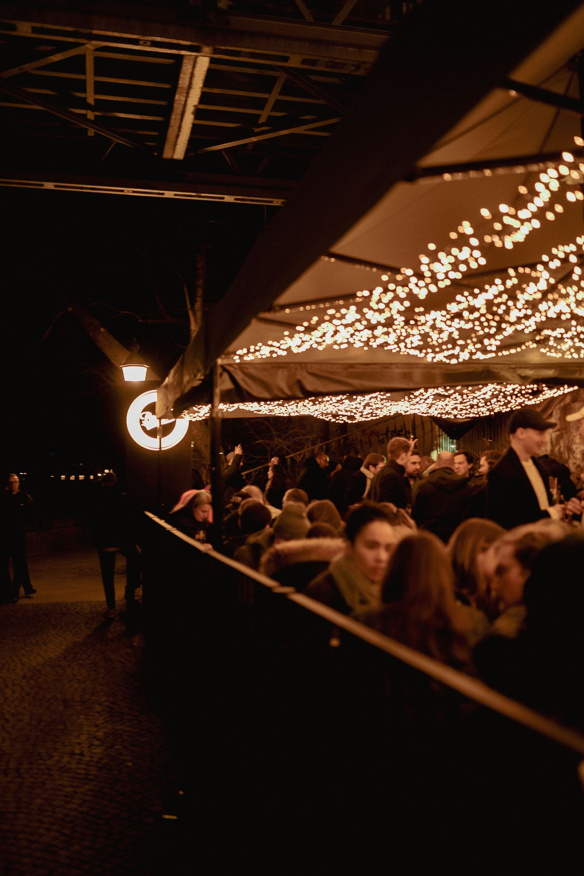 Volle Terrasse mit Lichterketten unter der Ludwigsbrücke – Boazn München, Adventszeit Dezember 2025 4