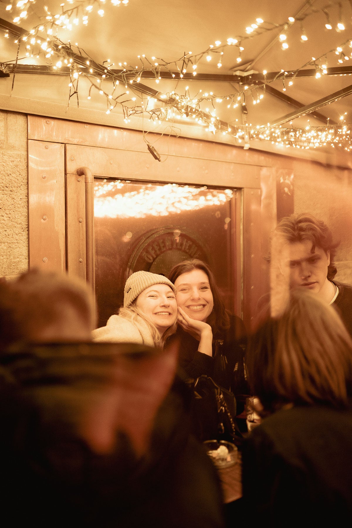 Zwei Freundinnen lachen unter funkelnden Lichterketten – Boazn München, Winterabend Dezember 2025 7