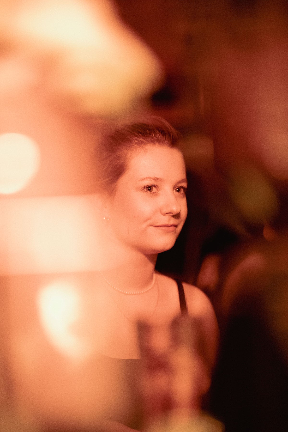 Portrait einer Gästin im warmen Licht der Boazn – Bar an der Isar, München, Dezember 2025 22