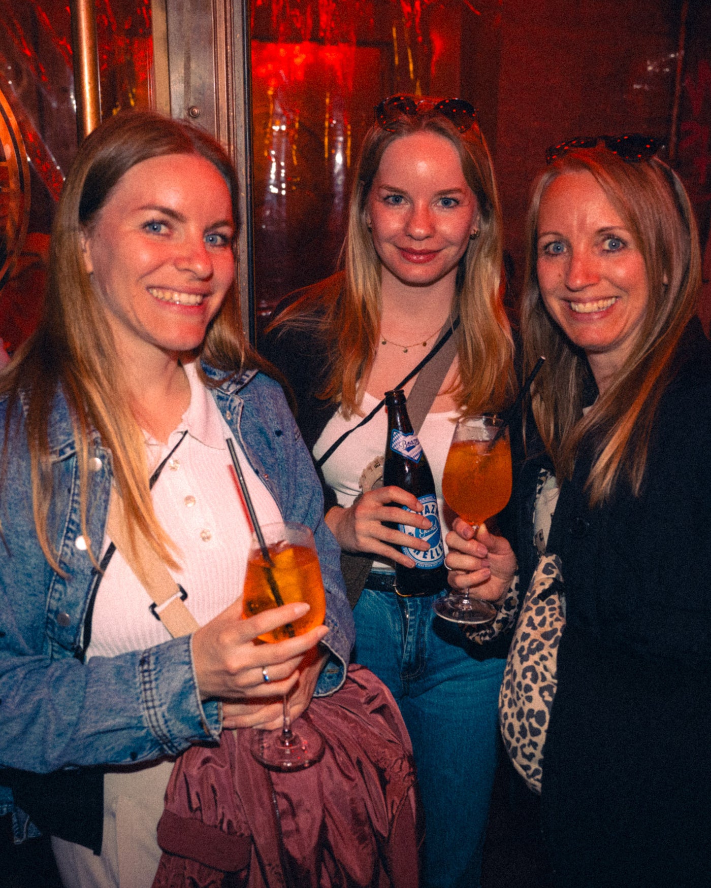 Drei Freundinnen lachen mit Aperol Spritz und Boazn Helles in der Hand – Boazn München, Bar an der Ludwigsbrücke, Mai 2026 8