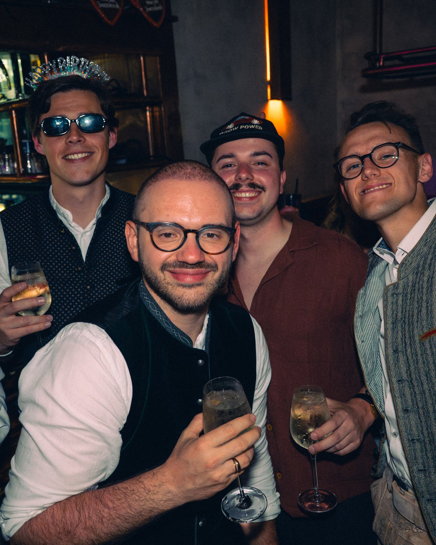 Vier Freunde im Vintage-Look stoßen mit Sektgläsern an – Boazn München, Tanzbar an der Ludwigsbrücke, Mai 2026 32