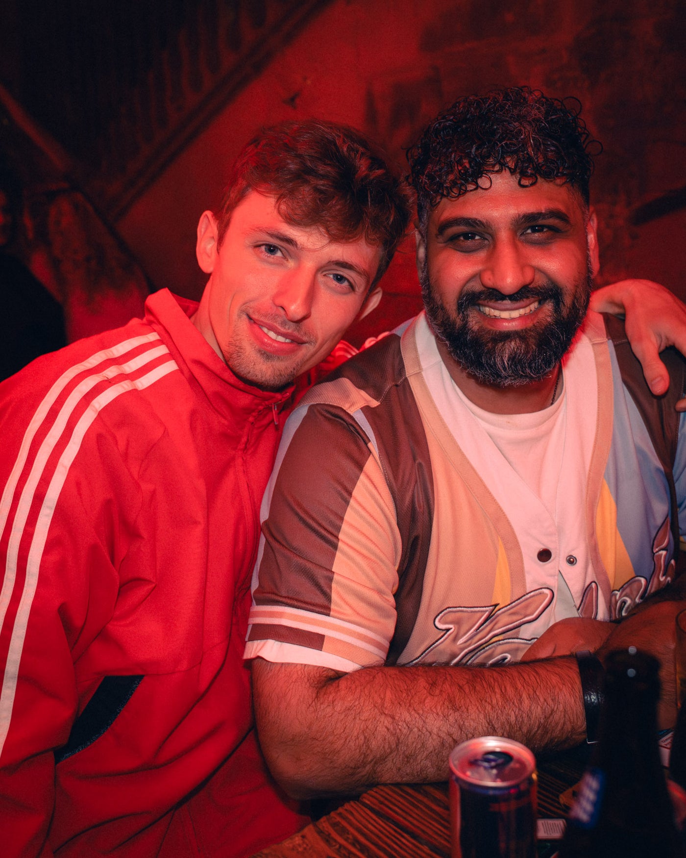 Zwei Männer eng nebeneinander, einer im roten Adidas-Anzug, lachen herzlich – Boazn München, Kneipe an der Isar, Mai 2026 35