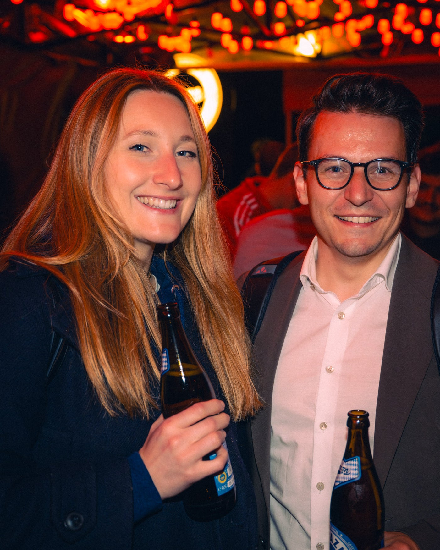 Pärchen mit Boazn-Helles-Flaschen lacht herzlich unter den Lichterketten – Boazn München, Kneipe an der Ludwigsbrücke, Mai 2026 40